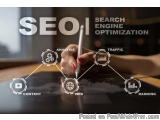 The image shows a person's hand holding a pen and drawing on a blackboard with the word "SEO" written in white text. Surround...