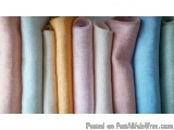 The image shows a group of rolled up fabric rolls in various colors. The rolls are arranged in a neat and orderly manner, wit...