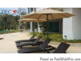 The image shows a group of black lounge chairs under a large beige umbrella. The umbrella is attached to a black pole and is...
