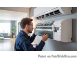 In this image, we can see a man wearing a blue shirt and glasses, working on an air conditioning unit. He is holding a tool i...