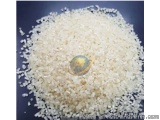 The image shows a pile of white rice grains on a black background. The rice grains are small and irregularly shaped, with som...