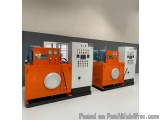 The image shows three large industrial machines in a room with a gray wall and white floor. The machines are orange in color...