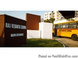 The image shows the entrance of Raj Vedanta School, a school in India. The entrance is marked by a large brown sign with the...