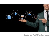 The image shows a man in a suit and tie holding a tablet in his hand. He is pointing to a set of six hexagonal icons on the s...