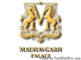 The image is a logo for Madhavgarh Palace, a luxury hotel in India. The logo is in the shape of a shield with two horses on e...