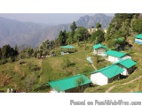The image shows a beautiful landscape of a mountainous area. There are several green-roofed huts scattered throughout the ima...