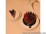 The image shows two round cakes on a beige surface. The cake on the left is a slice of chocolate cake with a slice taken out...