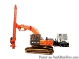 The image shows an orange-colored excavator with a long arm extended upwards. The arm is attached to a black-colored vehicle...