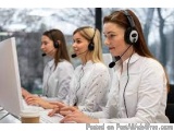 The image shows three young women wearing white lab coats and headsets, sitting in front of a computer monitor in a call cent...