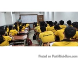 The image shows a classroom full of students sitting at their desks. They are all wearing yellow t-shirts with the words "Sri...