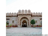 The image shows a large, ornate entrance gate of a fort. The gate is made of stone and has a large archway in the center. The...