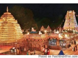 The image shows a beautiful Hindu temple at night. The temple is located in a park-like setting with trees in the background....