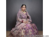 The image is a portrait of a young Indian woman wearing a traditional Indian bridal outfit. She is sitting on a wooden floor...