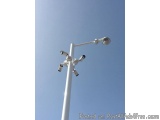 The image shows a tall white pole with multiple CCTV cameras attached to it. The pole is tall and slender, with a curved top...