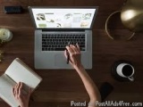 The image shows a person's hands typing on a laptop keyboard. The laptop is placed on a wooden desk with a cup of coffee and...