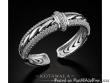 The image is a black and white photograph of a silver cuff bracelet. The bracelet is made of metal and has a twisted design w...
