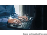 The image shows a person's hand typing on a laptop keyboard. The laptop is placed on a desk and the background is blurred. Th...