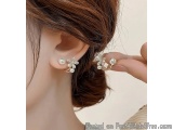 The image shows a close-up of a woman's ear. She is wearing a pair of earrings that are in the shape of flowers. The earrings...