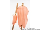 The image shows a wooden clothes rack with two clothes hanging on it. The top is a peach-colored kaftan with intricate white...