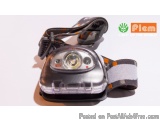 The image shows a small, compact headlamp with a strap attached to it. The strap is made of a gray and white striped fabric w...