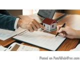 The image shows a person's hand holding a pen and signing a document on a clipboard. The document appears to be a real estate...