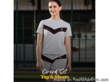 The image shows a young woman standing on a tennis court. She is wearing a white t-shirt with a chevron design on the front a...