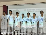 The image shows a group of nine young people standing in front of a whiteboard with the text "St. Mother Teresa School of Nur...