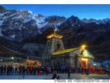 The image shows a group of people gathered around a temple in a mountainous area. The temple is located in the center of the...