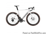 The image is of a white and black Canyon Ultimate CF SLX 9.0 road bike. The bike has a sleek and modern design with a white f...