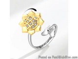 The image is of a ring with a unique design. The ring is made of silver and gold, with a large yellow flower-shaped pendant i...
