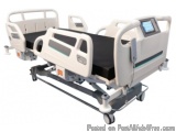 The image shows a hospital bed with a white frame and a black mattress. The bed has two headrests on either side and a footre...