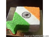The image is a photograph of a square-shaped cake with the flag of India on it. The cake is made of a light-colored sponge, w...