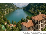 The image is an aerial view of a beautiful lake surrounded by lush greenery. The lake is a deep blue color and is surrounded...