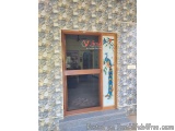 The image shows the entrance of a building with a glass door. The door is made of wood and has a wooden frame. The wall behin...