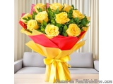 The image is of a beautiful bouquet of yellow roses. The bouquet is wrapped in red and yellow paper and tied with a yellow ri...