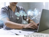 The image shows a young man wearing a grey scrub suit and a stethoscope around his neck, sitting at a desk with a laptop in f...