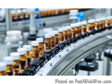 The image shows a conveyor belt in a factory or pharmaceutical industry. The belt is made of metal and has multiple rows of s...