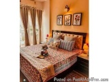 The image shows a bedroom with a large bed in the center. The bed has a wooden headboard and is covered with a red and white...