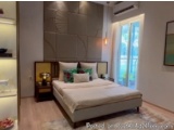 The image shows a modern and minimalist bedroom with a large window on the right side. The window has white curtains and is l...
