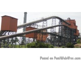 The image shows a large industrial plant with a conveyor belt running through it. The conveyor belts are made of metal and ar...