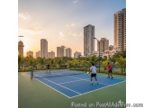 The image shows a tennis court in an urban area with tall buildings in the background. The court is blue and green in color a...