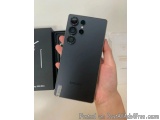 The image shows a person's hand holding a black Samsung Galaxy S20 Ultra smartphone. The phone has a sleek design with a trip...