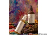 The image shows two bottles of hair care products on a colorful background. The bottles are placed on a piece of driftwood wi...