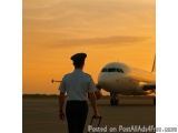 The image shows a man in a uniform, possibly a pilot, walking towards an airplane on the tarmac at sunset. The man is wearing...