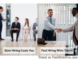 The image shows a group of people in a meeting room, with a man shaking hands with another man. The man shaking the hand is w...