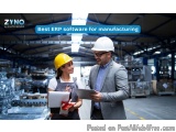 The image shows a man and a woman in a factory setting. They are both wearing hard hats and are standing in front of a large...