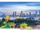 The image is a panoramic view of a city skyline at dusk. The sky is a beautiful mix of blue and orange hues, with the sun set...