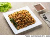 The image shows a plate of food on a beige tablecloth. The plate is white and rectangular in shape and is filled with a dish...