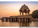 The image shows a beautiful sunset over a body of water. In the center of the image, there is a large, ornate structure with...