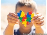 The image shows a young boy holding a heart-shaped puzzle piece in front of his face. The puzzle piece is made up of multiple...